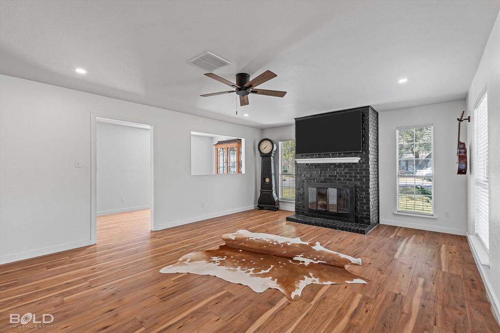 3407 Hickory Ridge Road Shreveport, LA 71108 - Photo 10 of 35 Unfurnished living room featuring healthy amount of natural light, a fireplace, light wood-type flooring, a ceiling fan, and recessed lighting
