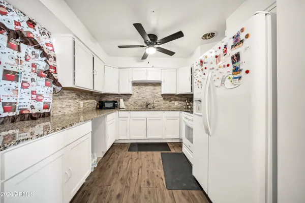 a kitchen with granite countertop white cabinets and white appliances