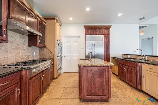a kitchen with granite countertop stainless steel appliances and wooden cabinets
