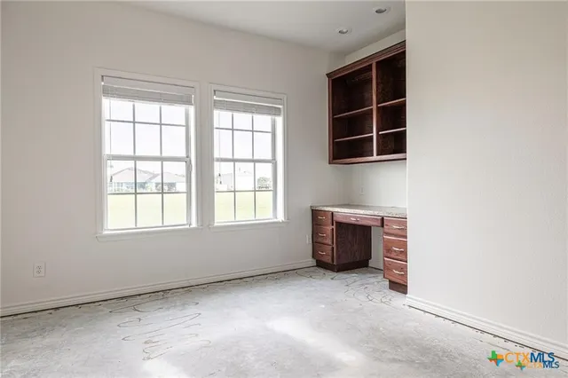an empty room with windows and cabinet