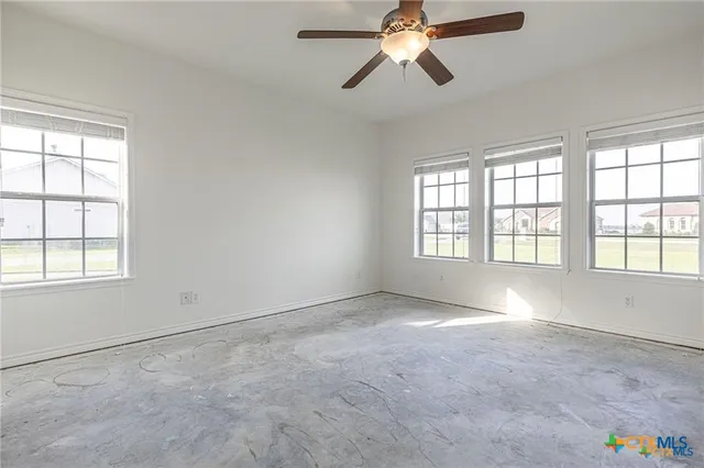 an empty room with windows and fan