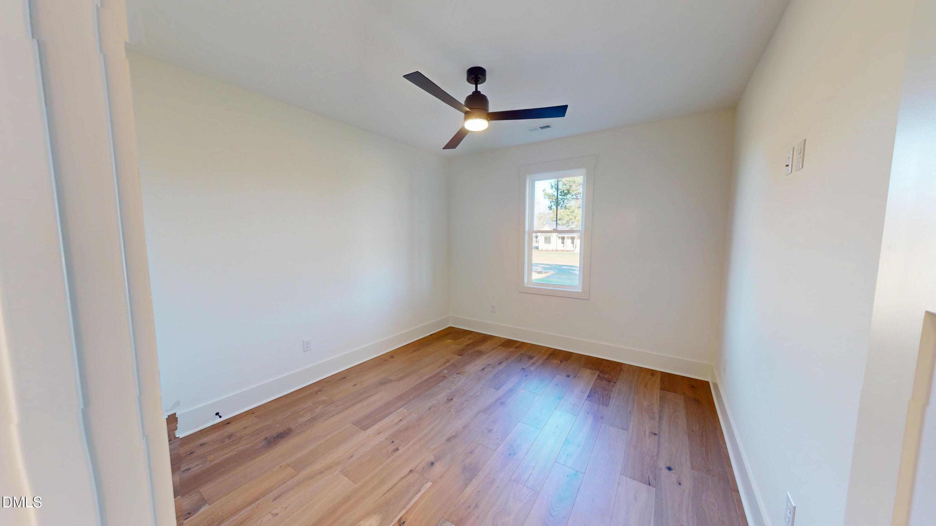 5009 Hopkins Chapel Road Zebulon, NC 27597 - Photo 19 of 28 an empty room with wooden floor ceiling fan and window