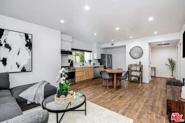 a living room with furniture kitchen view and a wooden floor