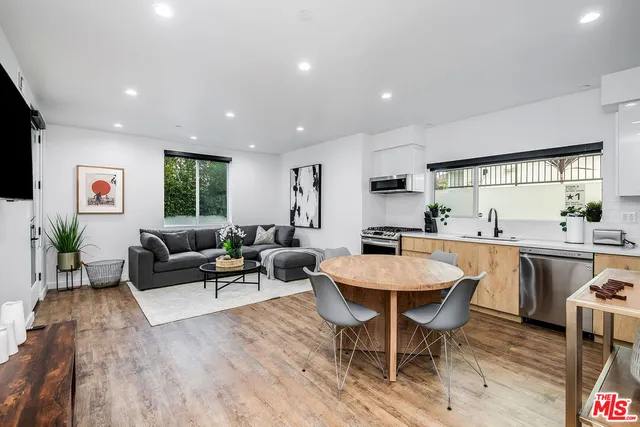 a living room with stainless steel appliances kitchen island a table and chairs in it