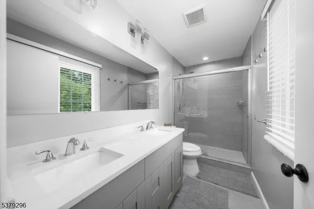 a bathroom with a double vanity sink toilet and shower