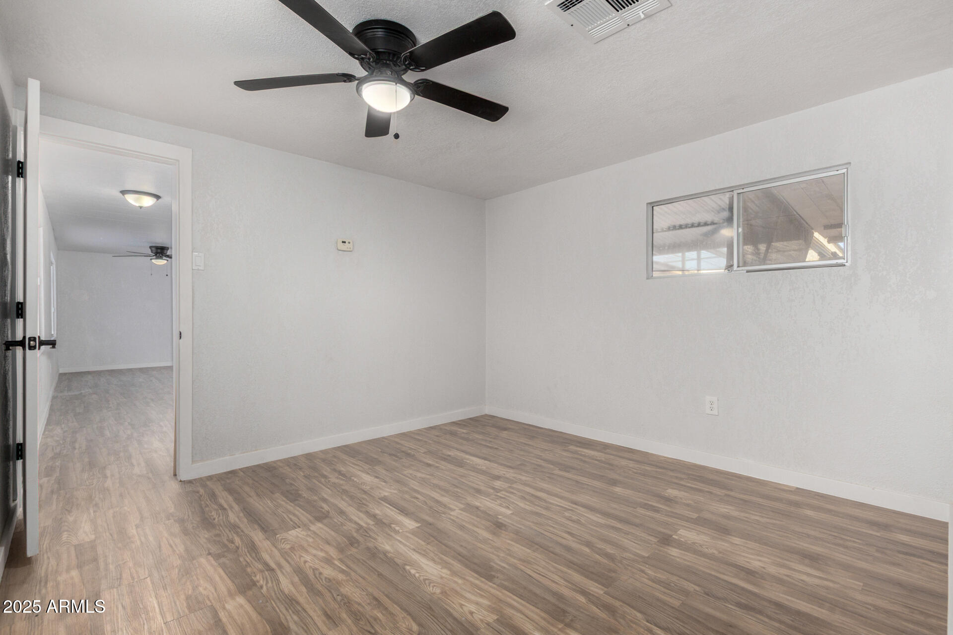 2050 West Dunlap Avenue, Unit D42 Phoenix, AZ 85021 - Photo 7 of 30 an empty room with wooden floor and a ceiling fan