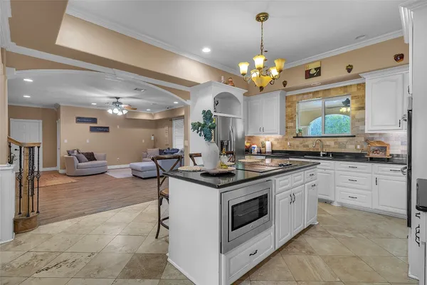 a kitchen that has a lot of white cabinets and stainless steel appliances