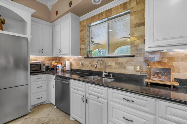 a kitchen with granite countertop white cabinets and sink