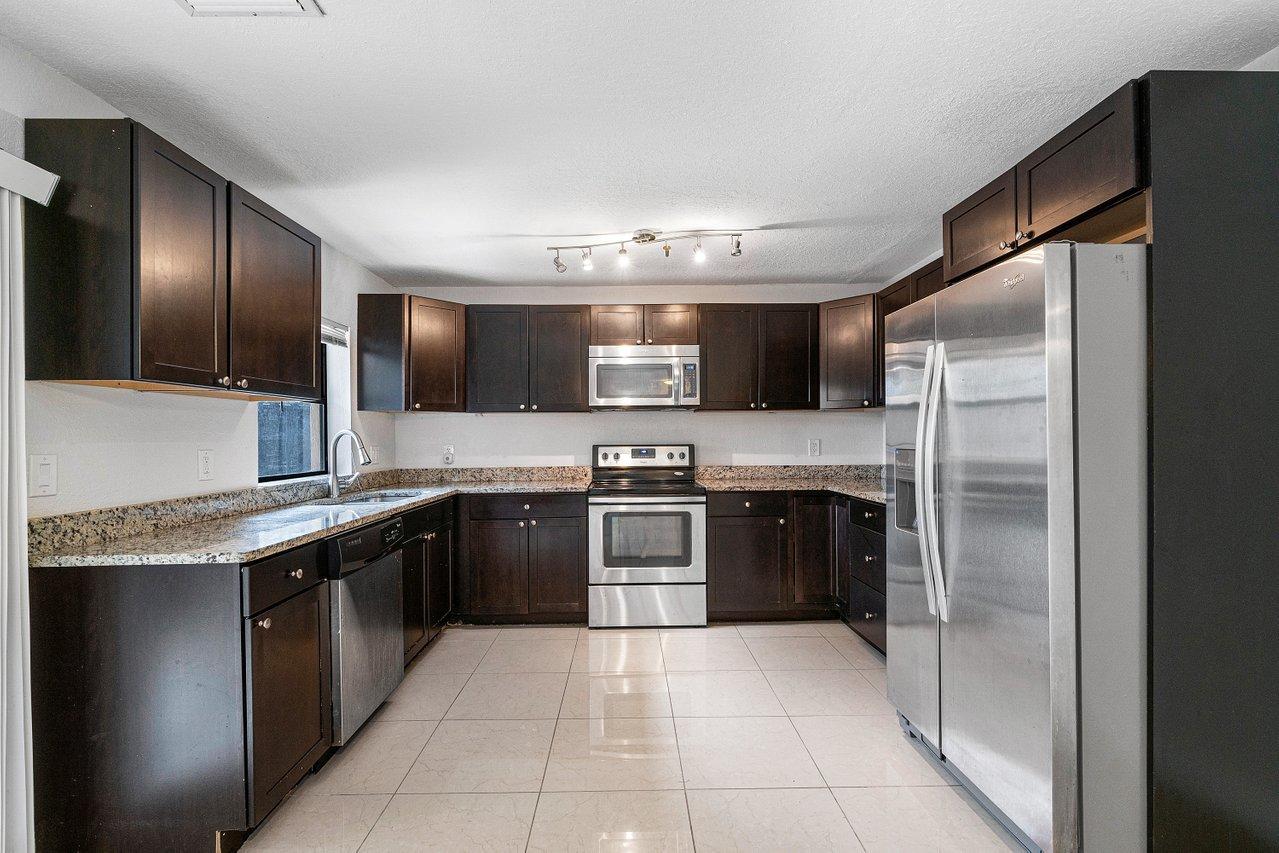 a large kitchen with stainless steel appliances granite countertop a refrigerator and a stove top oven