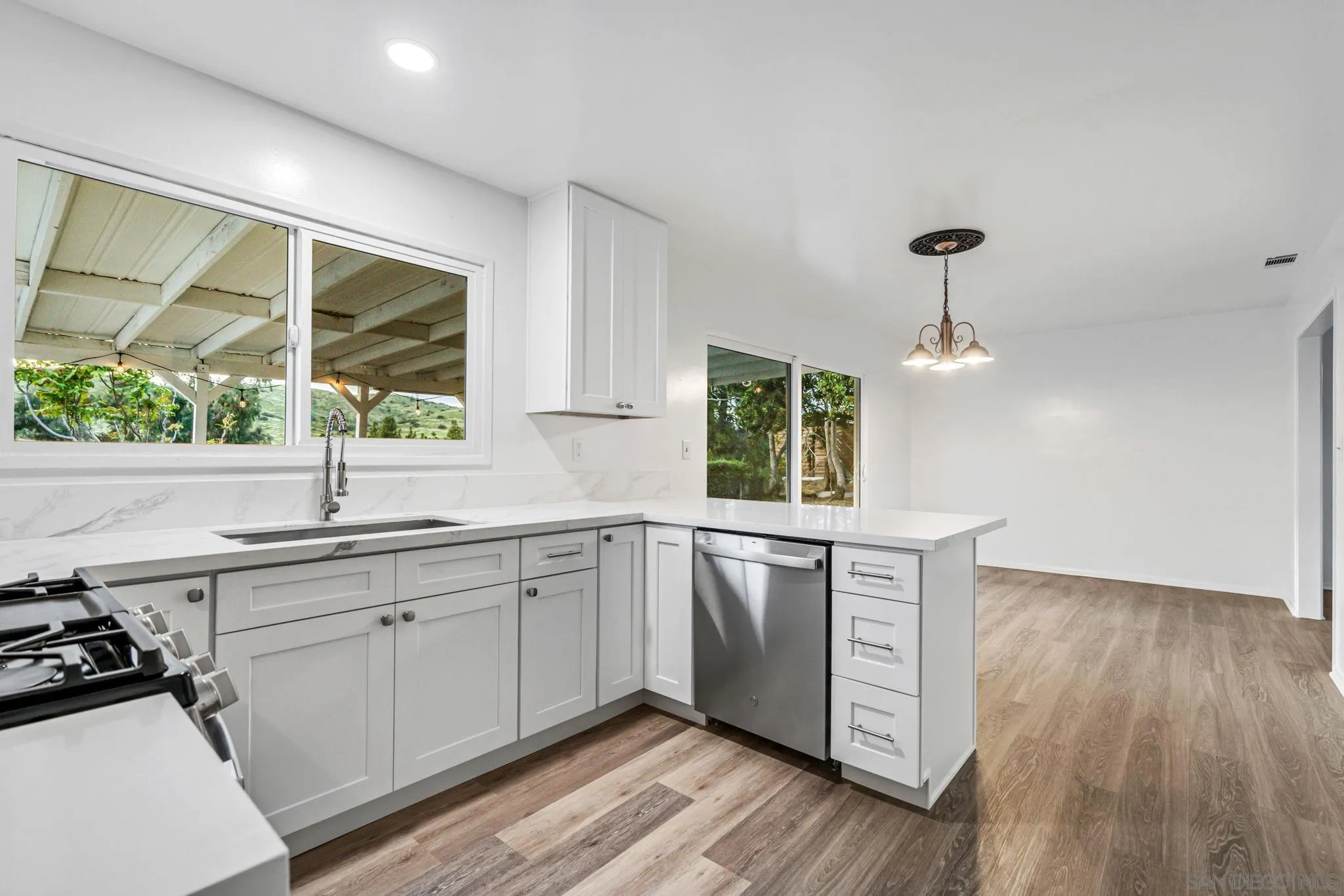 10330 Strathmore Drive Santee, CA 92071 - Photo 7 of 21 a kitchen with stainless steel appliances granite countertop wooden floors and sink