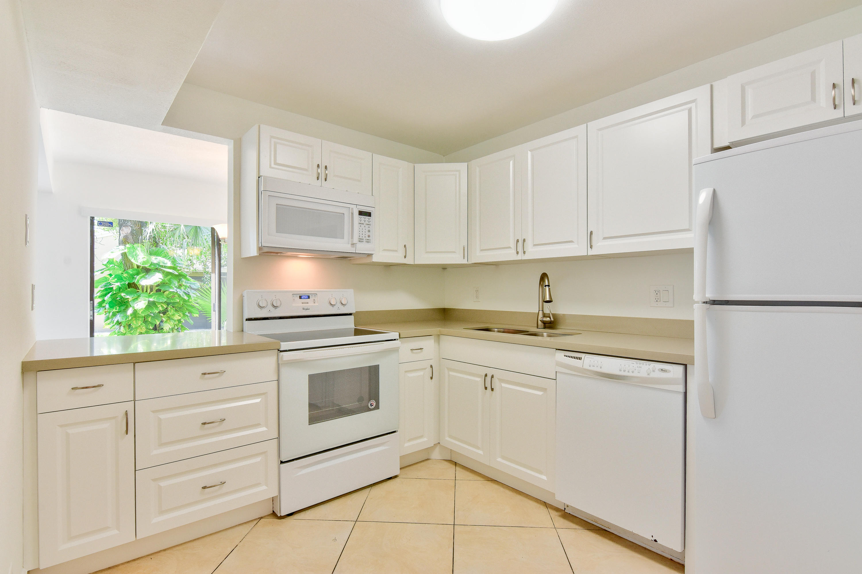 1149 Northwest 13th Street, Unit 7 Boca Raton, FL 33486 - Photo 4 of 14 a kitchen with granite countertop white cabinets and white appliances