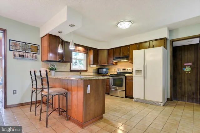 a kitchen with stainless steel appliances granite countertop a refrigerator and a stove top oven