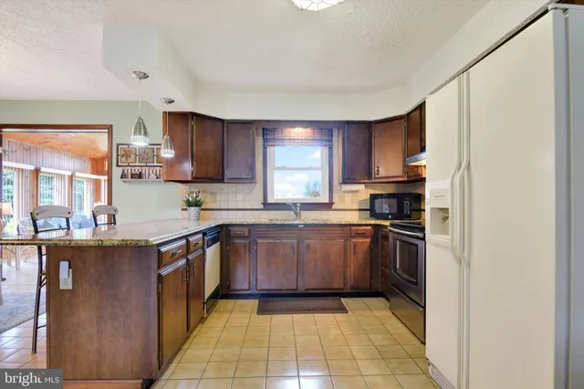 a kitchen with stainless steel appliances granite countertop a stove top oven a sink dishwasher a refrigerator and cabinets