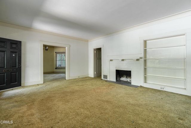 a view of an empty room with a fireplace and a window