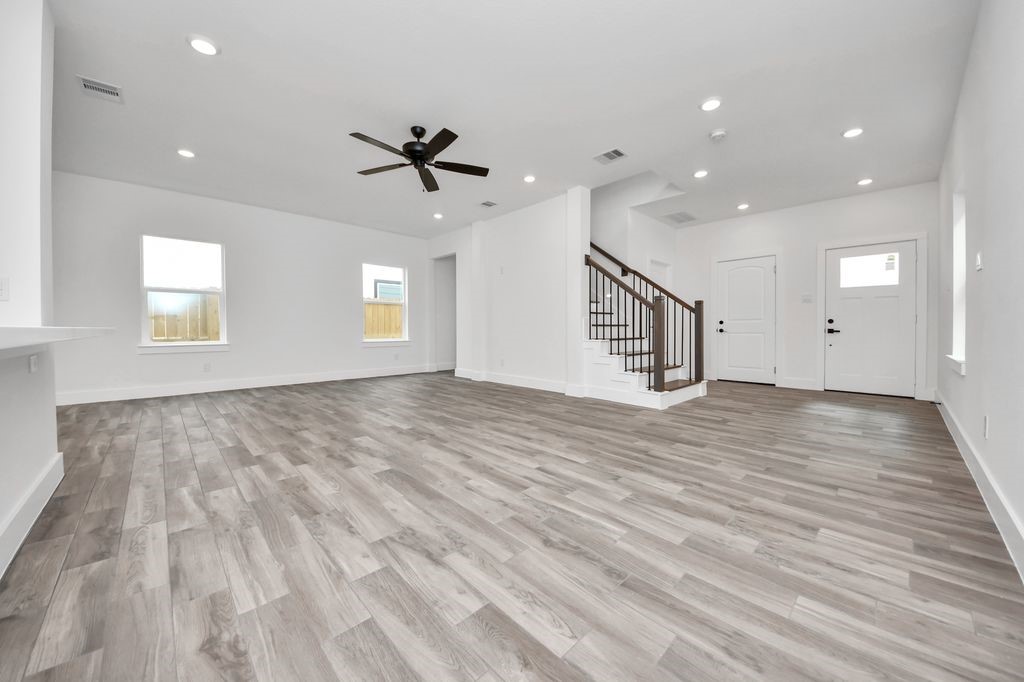 767 Marjorie Street Houston, TX 77088 - Photo 9 of 20 an empty room with wooden floor ceiling fan and windows
