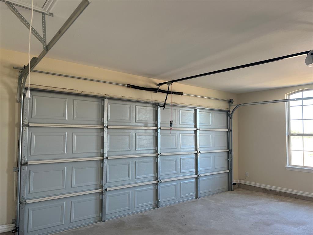 8008 County Road 1058 Rice, TX 75155 - Photo 23 of 25 Spacious garage featuring a light gray paneled garage door, exposed metal track system, and an automatic garage door opener