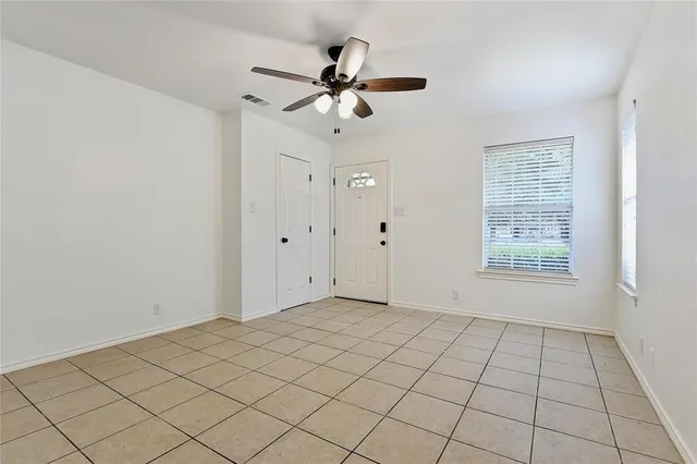an empty room with a hallway and a chandelier fan