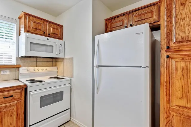 a white refrigerator freezer and a stove sitting inside of a kitchen