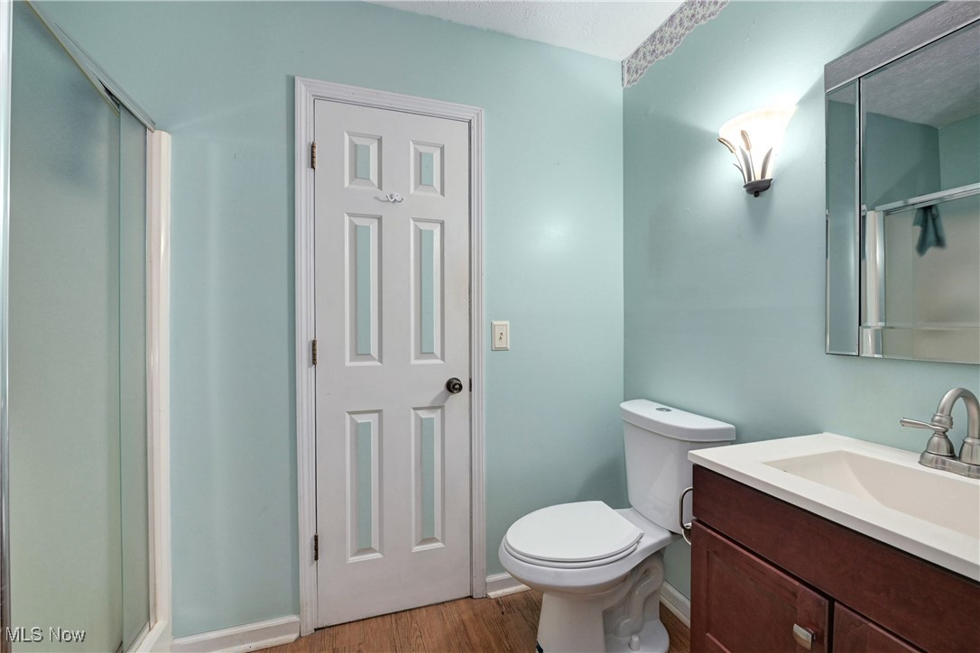 1820 Claus Road Vermilion, OH 44089 - Photo 6 of 10 Bathroom featuring vanity, toilet, hardwood / wood-style floors, and a shower with door