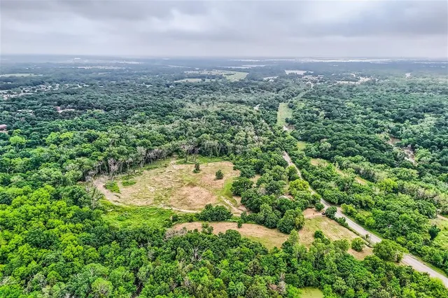 an aerial view of residential houses with outdoor space and trees
