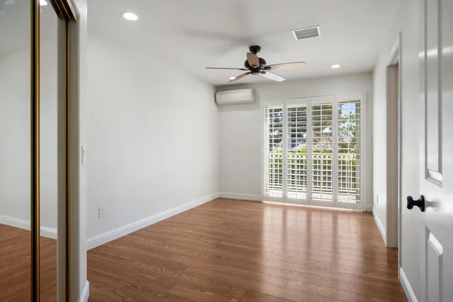 an empty room with wooden floor fan and windows