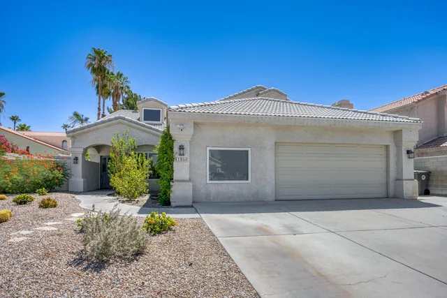 a front view of a house with a yard and potted plants