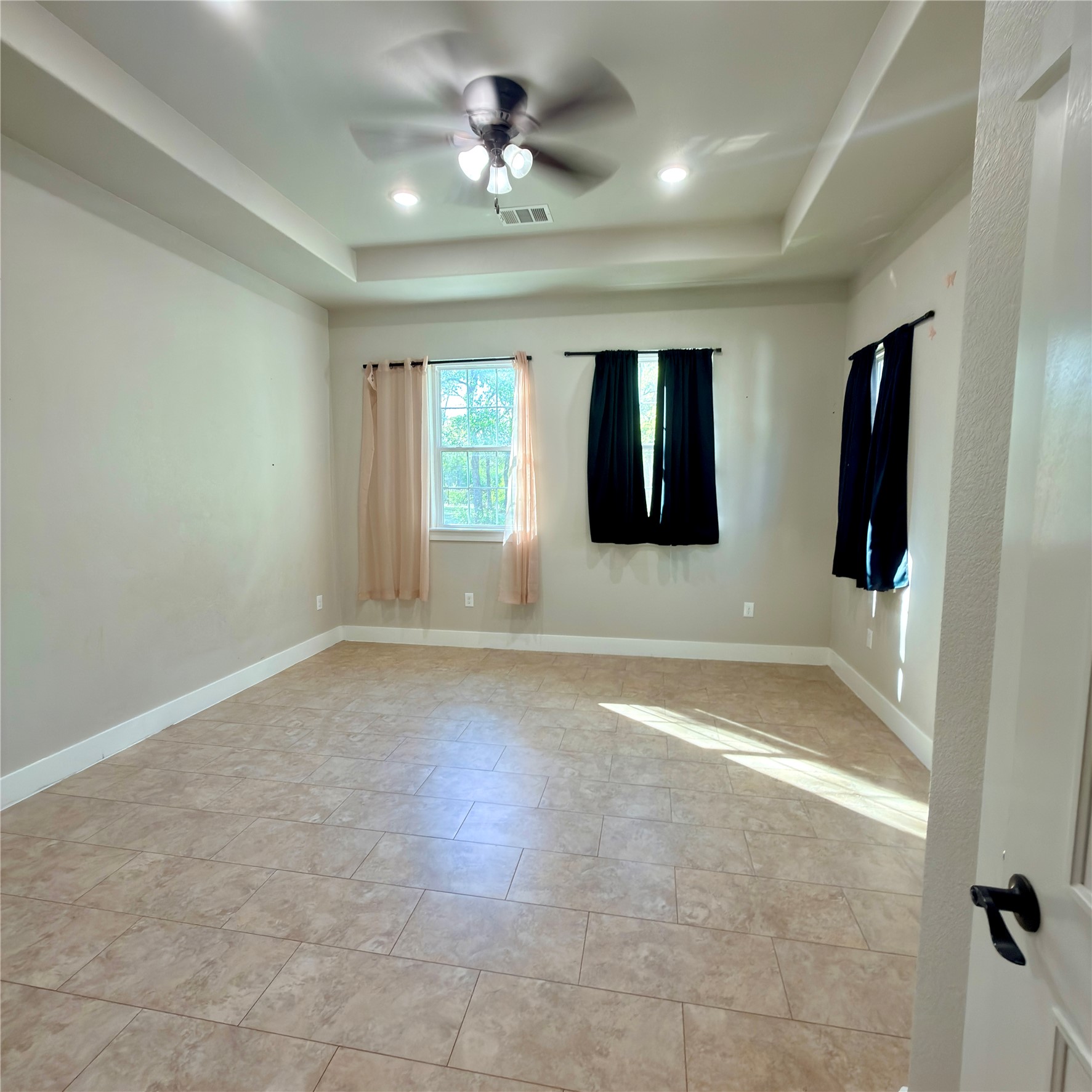 127 Comanche Trail, Unit A Elgin, TX 78621 - Photo 11 of 33 Unfurnished room featuring ceiling fan, light tile patterned floors, and a raised ceiling