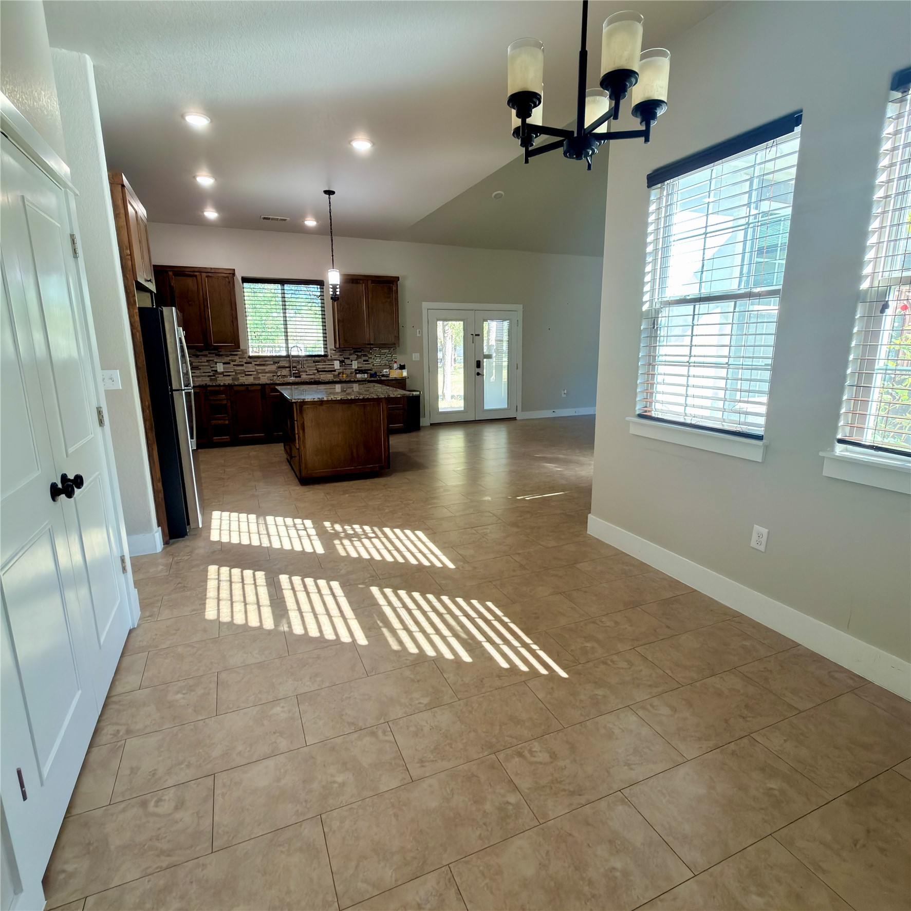 127 Comanche Trail, Unit A Elgin, TX 78621 - Photo 33 of 33 Kitchen with a kitchen island, open floor plan, freestanding refrigerator, tasteful backsplash, and dark wood finish cabinets