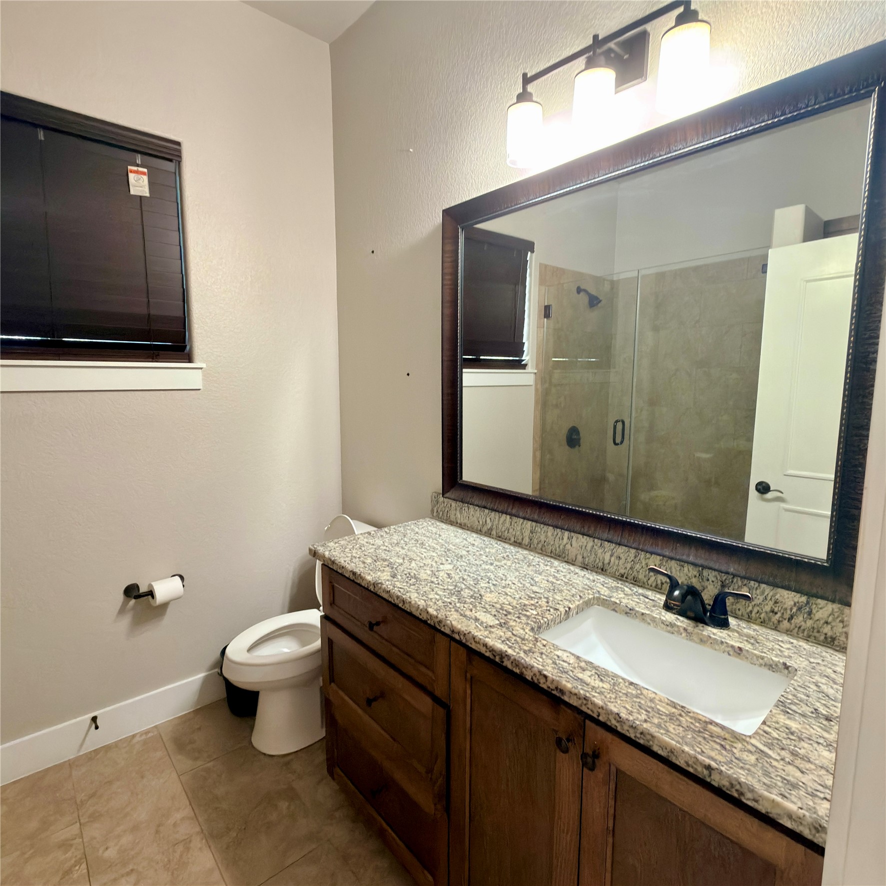 127 Comanche Trail, Unit A Elgin, TX 78621 - Photo 18 of 33 Full bath with a shower stall, a textured wall, vanity, and light tile patterned flooring