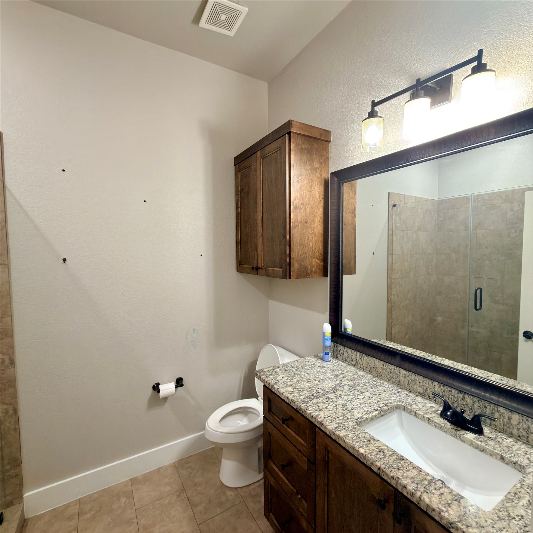 127 Comanche Trail, Unit A Elgin, TX 78621 - Photo 6 of 33 Full bath with vanity, a shower stall, light tile patterned floors, and a textured wall