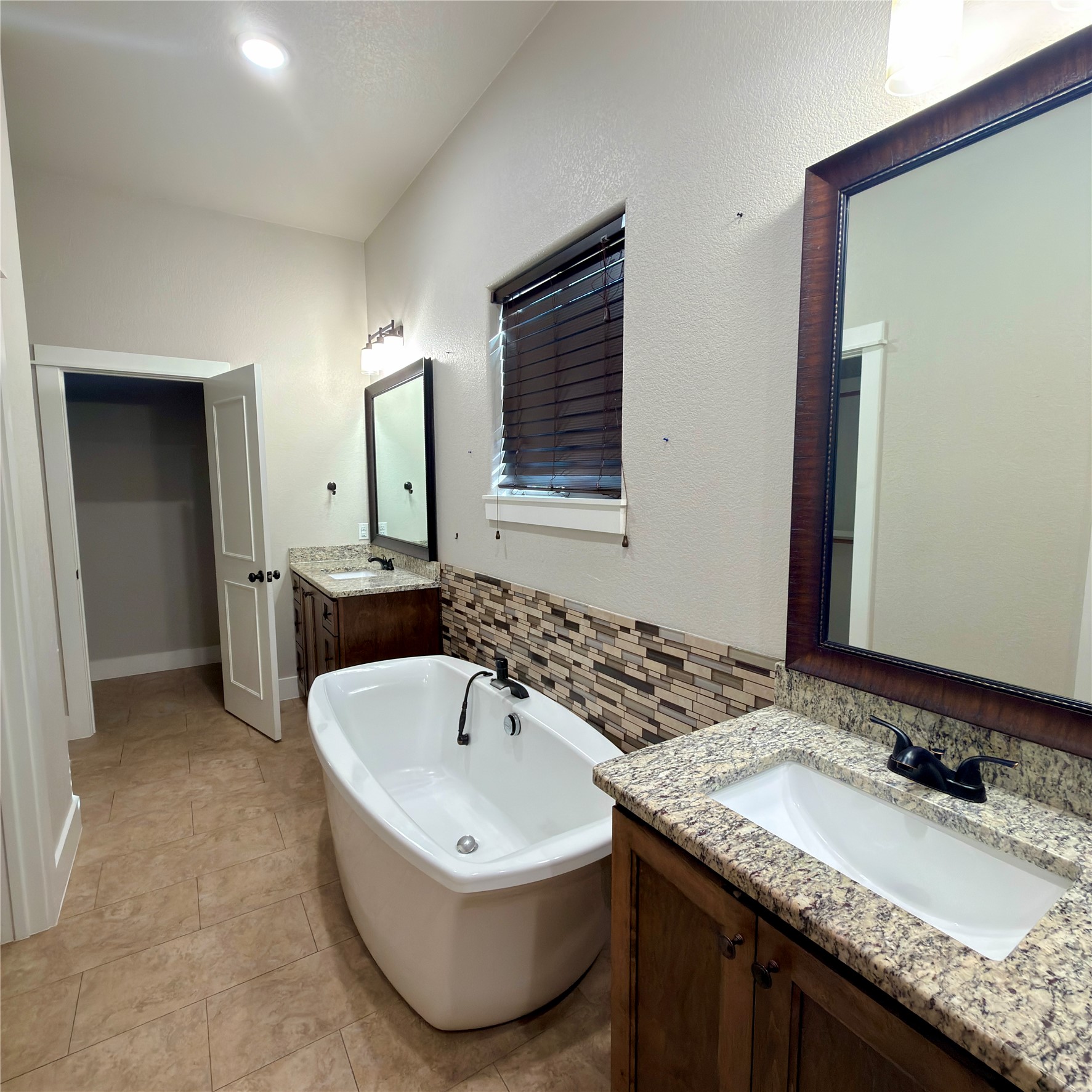 127 Comanche Trail, Unit A Elgin, TX 78621 - Photo 9 of 33 Full bath featuring two vanities, a soaking tub, and light tile patterned flooring
