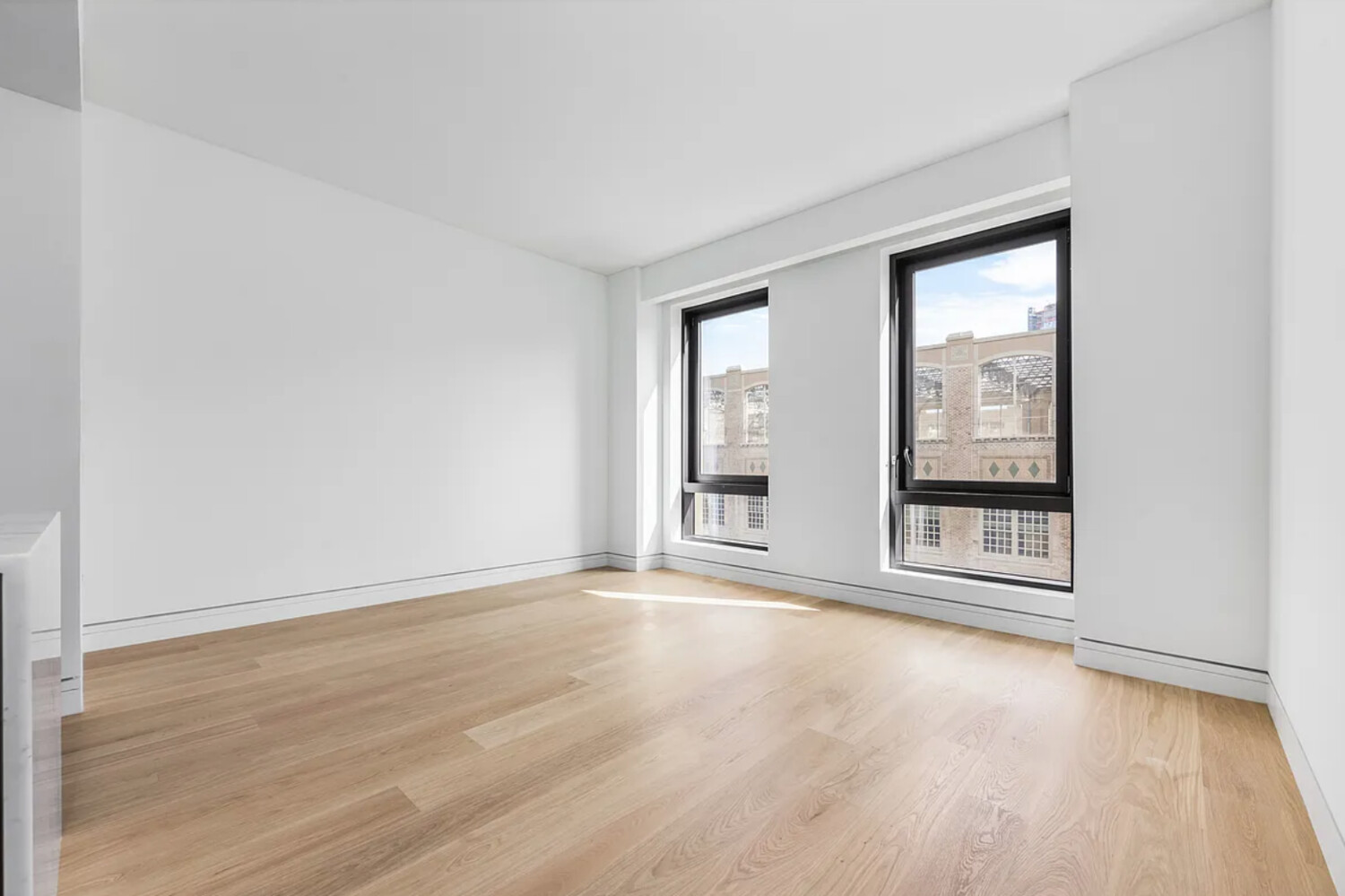 242 Broome Street, Unit 10B Manhattan, NY 10002 - Photo 2 of 10 an empty room with wooden floor and windows