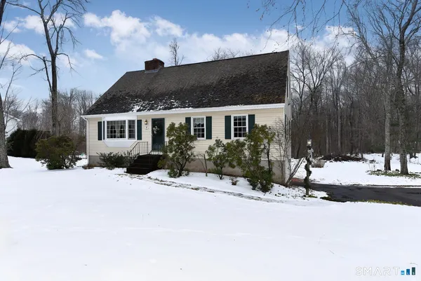 a front view of a house with a yard covered with snow