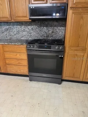 a kitchen with granite countertop cabinets appliances and a wooden floor