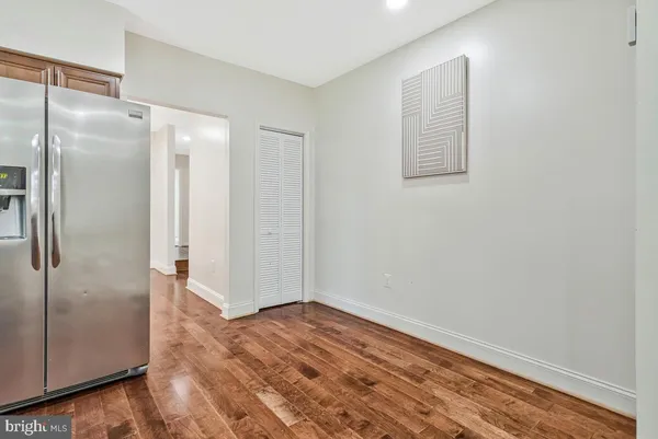 a view of an empty room with wooden floor and a bathroom
