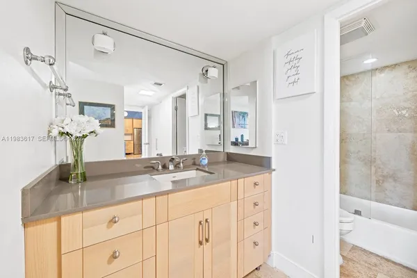 a bathroom with a granite countertop sink a mirror and a shower