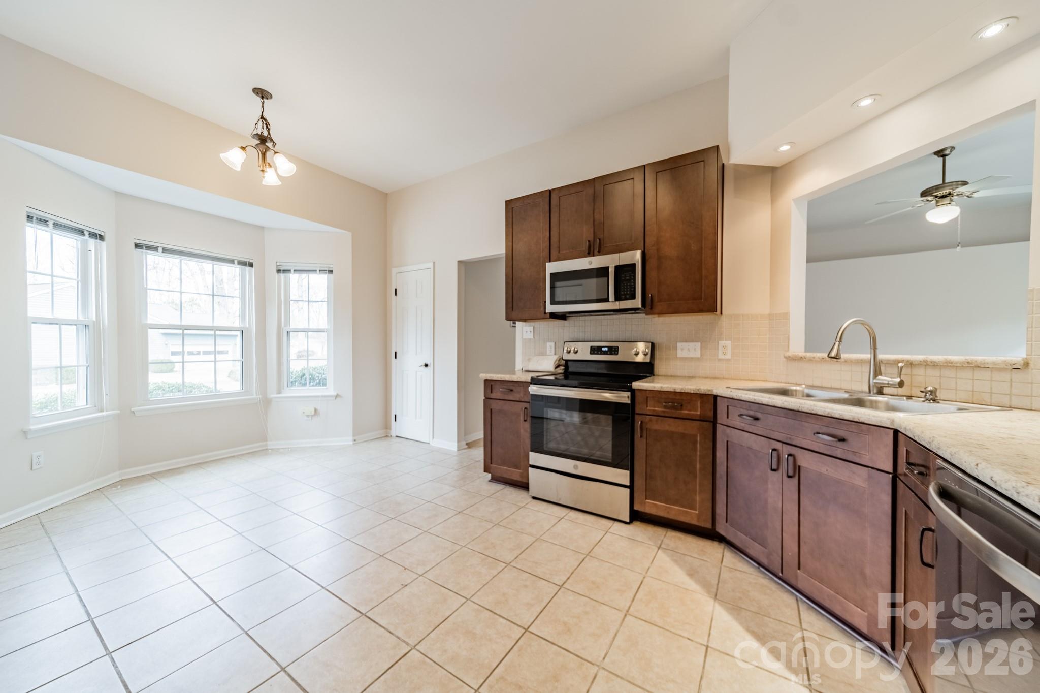 9409 Cedar River Road Huntersville, NC 28078 - Photo 17 of 31 a kitchen with stainless steel appliances granite countertop a stove top oven a sink dishwasher and a refrigerator with wooden floor