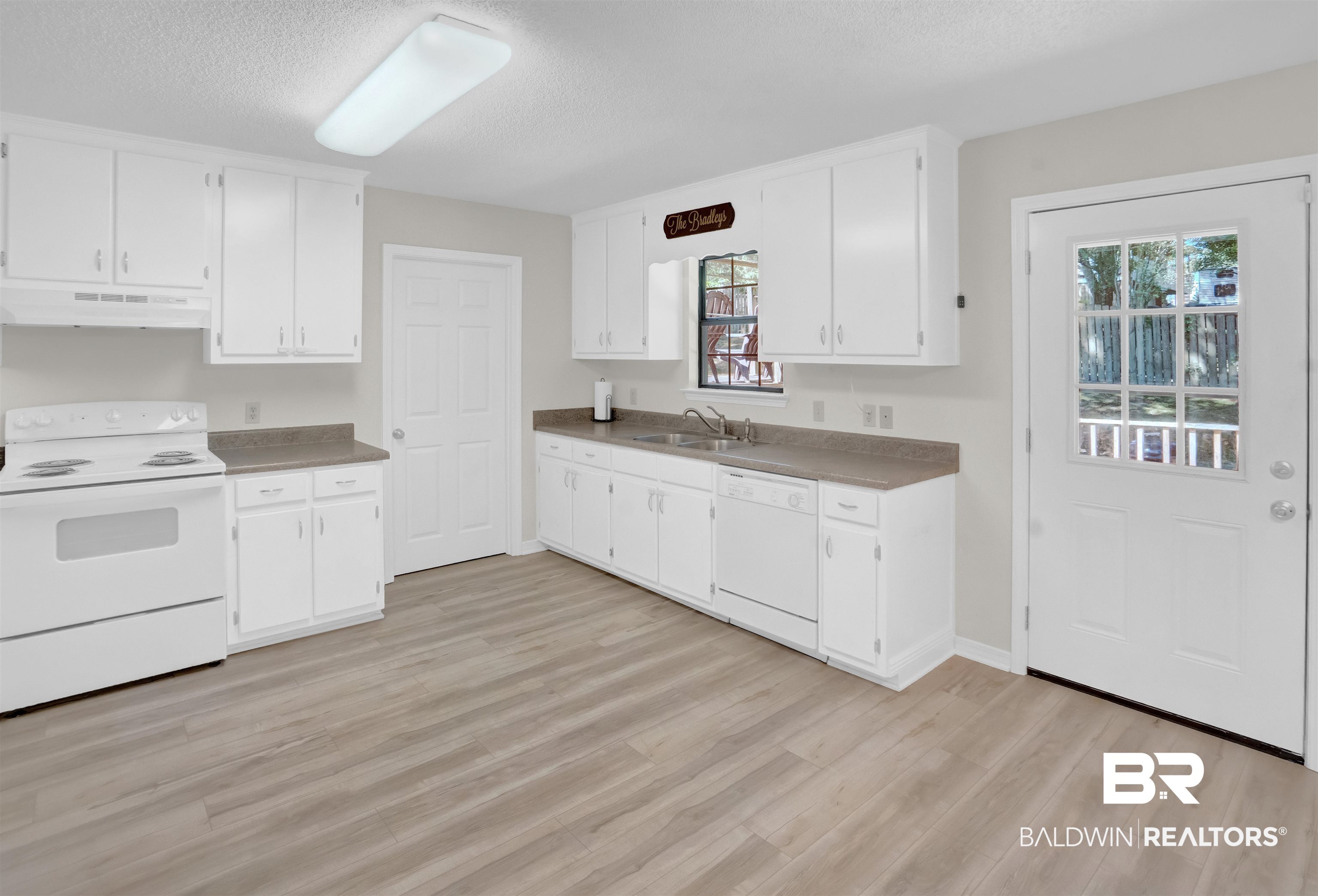 30871 Stanton Road Spanish Fort, AL 36527 - Photo 13 of 35 Kitchen with sink, white appliances, white cabinets, and light hardwood / wood-style flooring