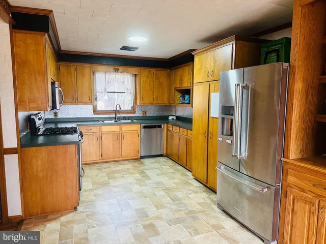 a kitchen with stainless steel appliances granite countertop a refrigerator a sink a stove a washer dryer and a dining table