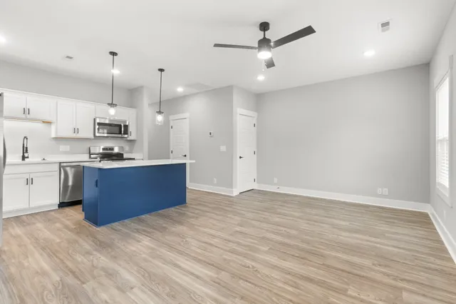 a kitchen with stainless steel appliances kitchen island granite countertop a sink and a refrigerator