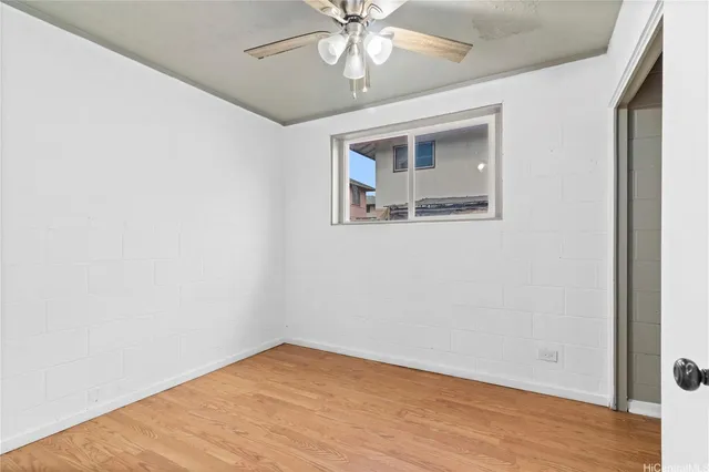 an empty room with wooden floor chandelier fan and windows