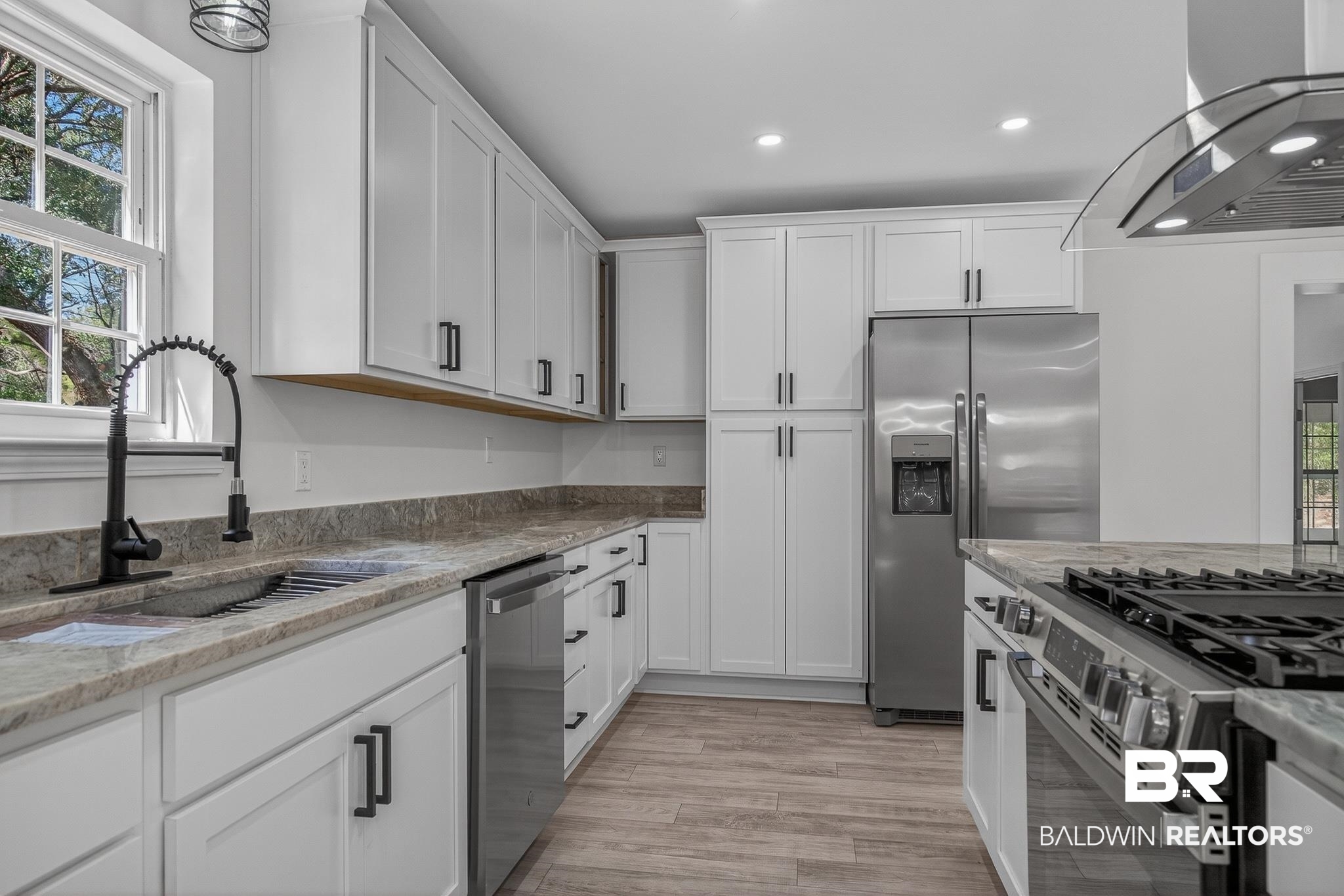10650 Old Pascagoula Road Theodore, AL 36582 - Photo 28 of 77 Kitchen with white cabinetry, stainless steel appliances, ventilation hood, light stone countertops, and light wood-style floors