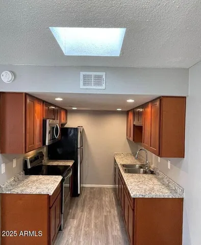a kitchen with granite countertop stainless steel appliances a sink stove top oven and cabinets