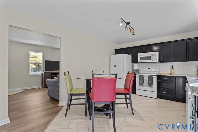 a kitchen with stainless steel appliances granite countertop a stove top oven a sink dishwasher a dining table and chairs with wooden floor