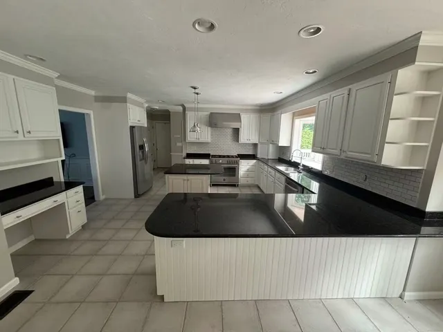 a kitchen with granite countertop a sink a stove and cabinets