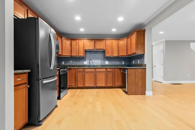a kitchen with stainless steel appliances granite countertop a refrigerator a sink and a stove