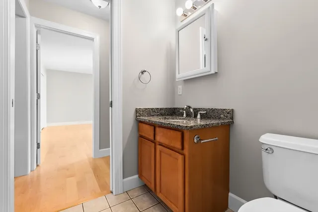 a bathroom with a granite countertop sink and a toilet