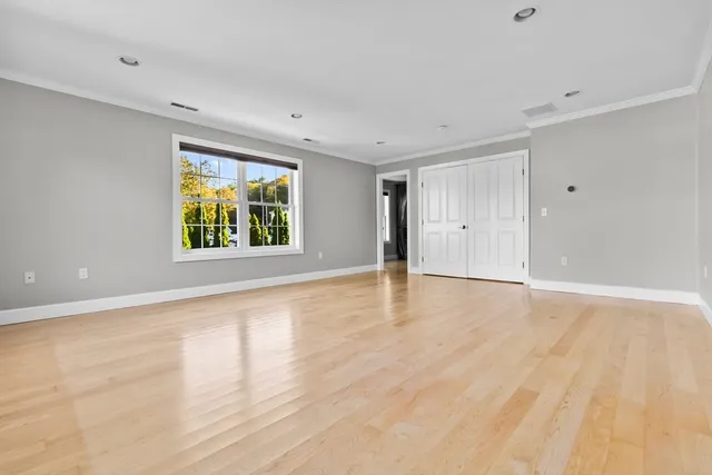 a view of an empty room with window and wooden floor