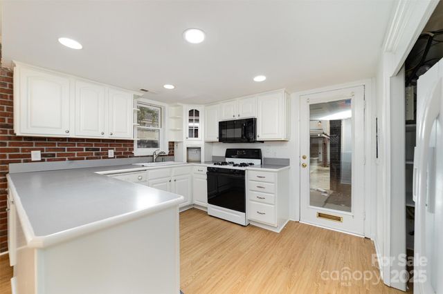 a kitchen with granite countertop a stove top oven a sink dishwasher and a refrigerator with wooden floor