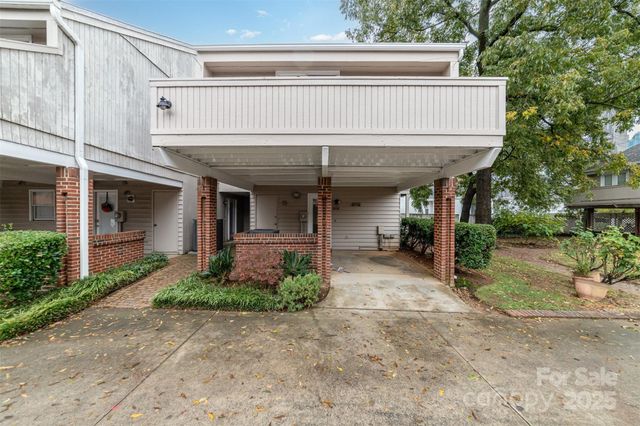 a view of a brick house with plants and large tree